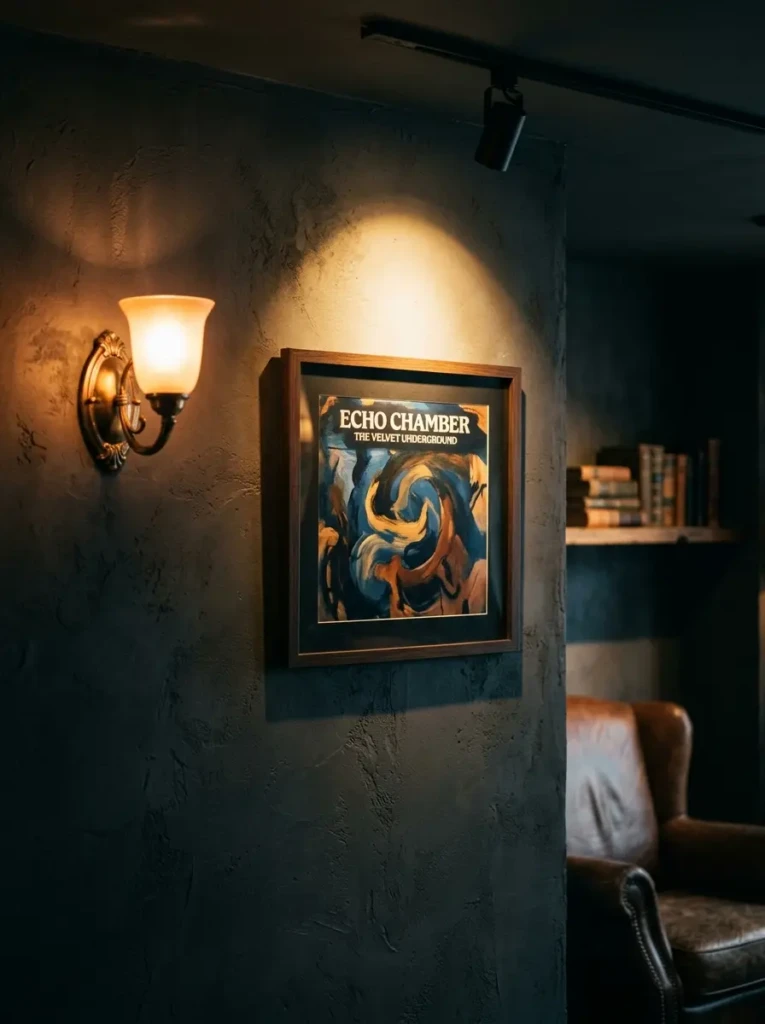 A framed album cover highlighted by a wall light, adding drama and emphasis to the decor.